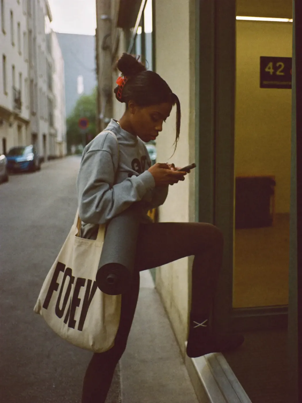 A woman carrying a yoga mat outside a city building