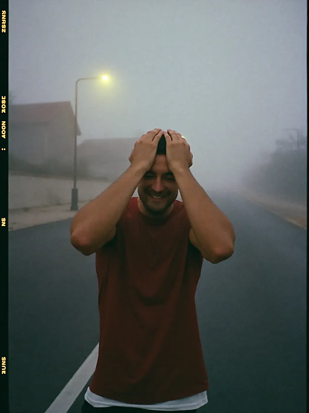 A runner laughing on a foggy road at dawn